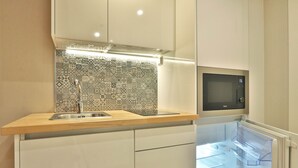 A modern kitchen with a patterned backsplash, a microwave, and a built-in refrigerator. - BOULEVARD Boutique Studios   (Lisbon)