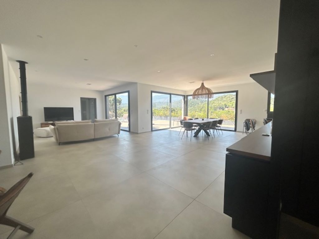 A spacious living area with a large sofa set, a dining table, and a TV.