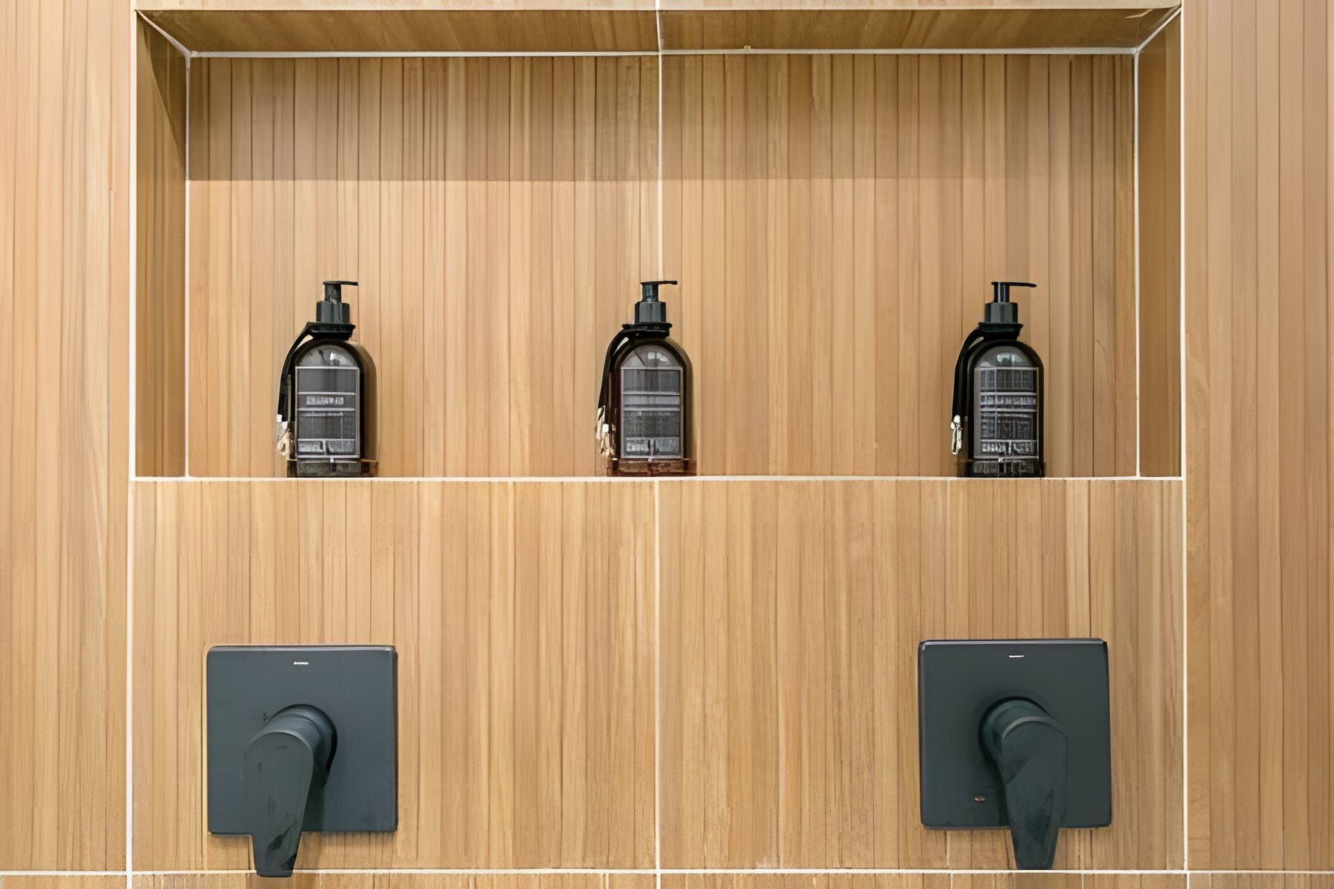 A wooden wall with three black dispensers and two black switches.