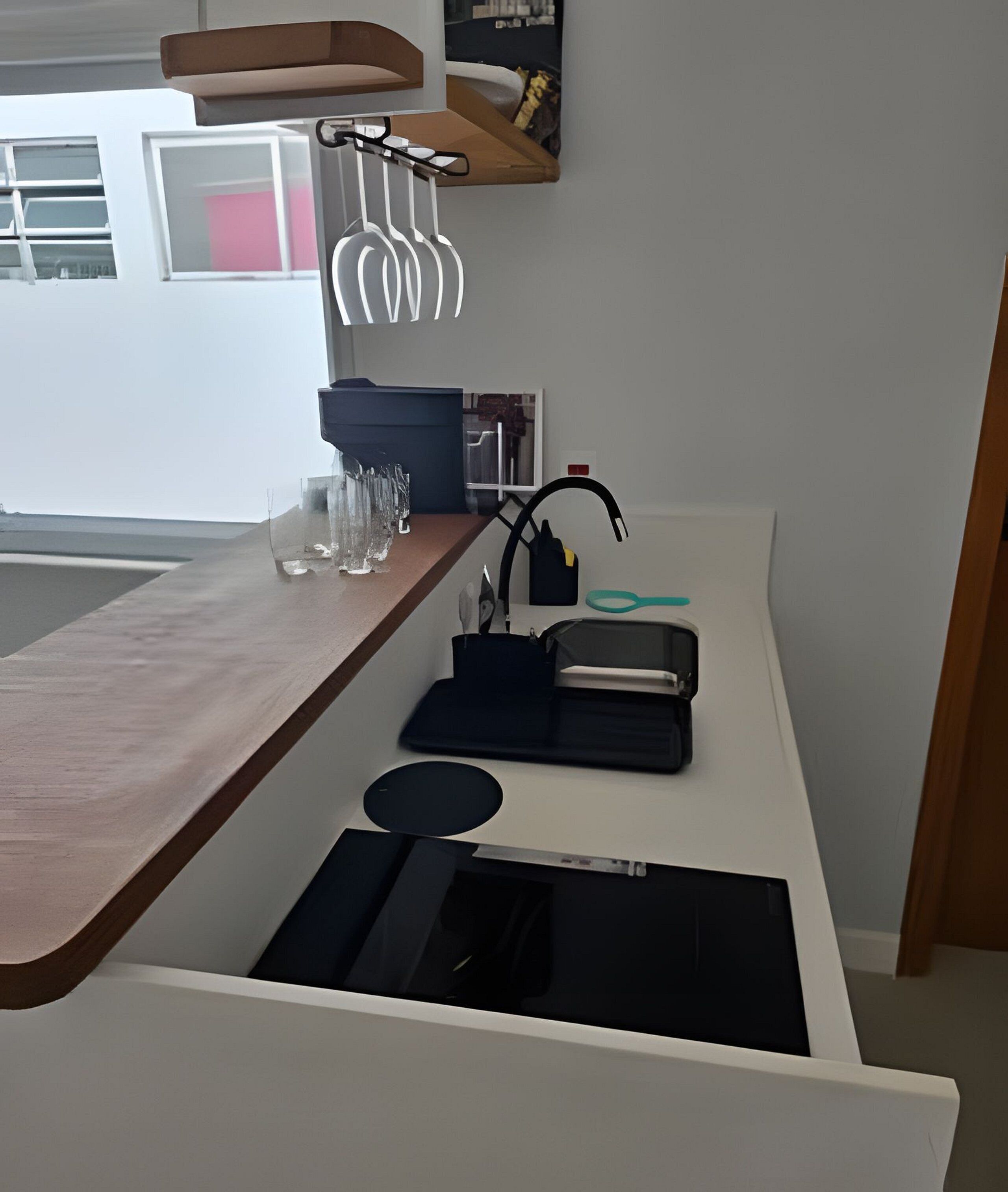 A modern kitchen with a wooden countertop, a built-in sink, and a hanging light fixture.