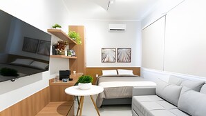 A modern, compact bedroom with a bed, a sofa, a small table, and shelves with plants. - chale leblon (Rio de Janeiro)