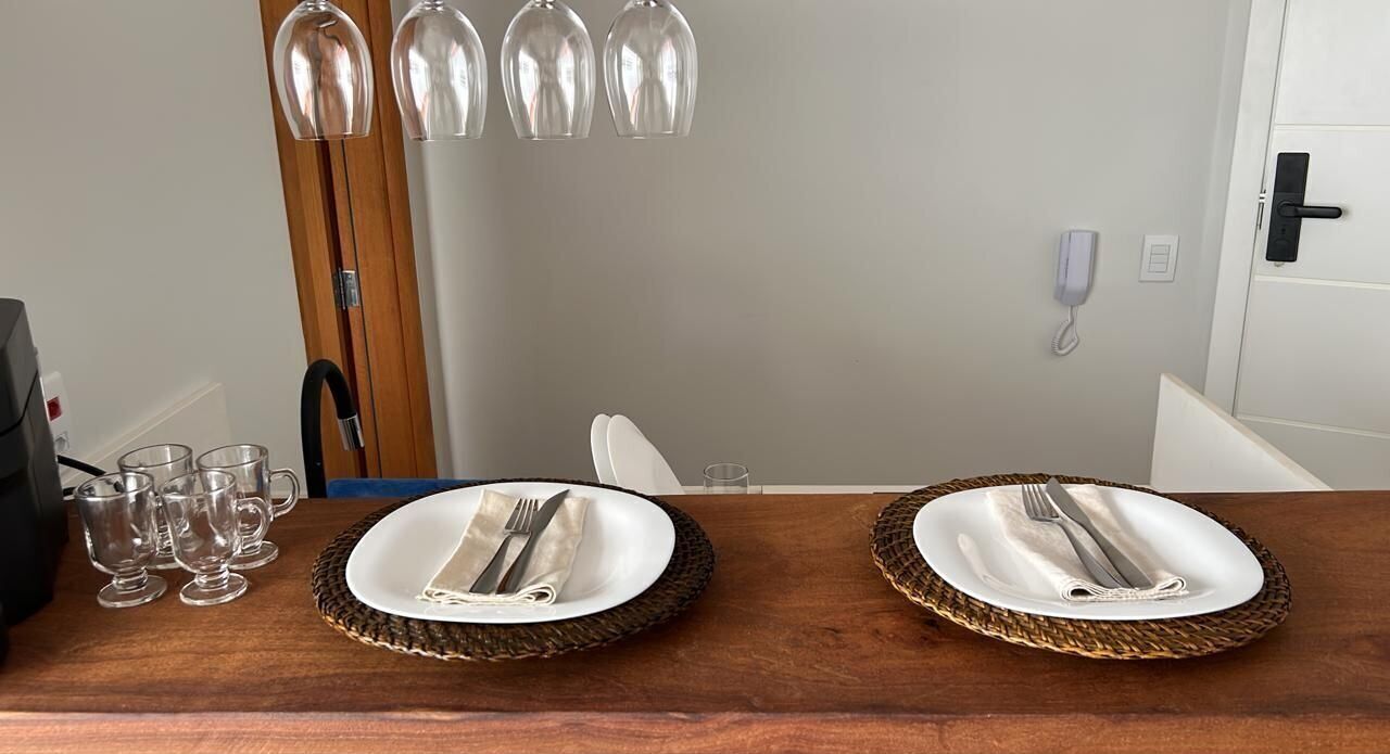 A dining table set with plates, cutlery, and glasses, with a telephone and a door in the background.
