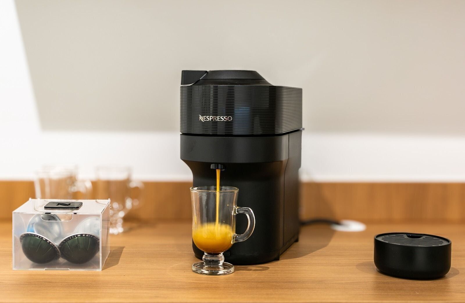 A Nespresso coffee machine dispensing coffee into a glass cup.