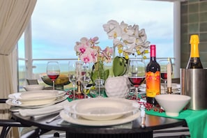 A table set for dining with plates, glasses, and a bottle of wine, overlooking a scenic view.