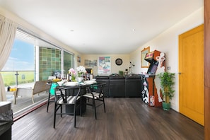 A spacious living area with a dining table, chairs, a sofa, and a basketball arcade game. - Whitewater Seaview (Newquay)