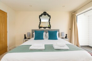A hotel room with a bed, two nightstands, a mirror, and a window with curtains. - Whitewater Seaview (Newquay)