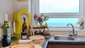 Eine Küchenarbeitsplatte mit Brot, Gebäck, einer Flasche Estrella Galicia Wein und einer Uhr.