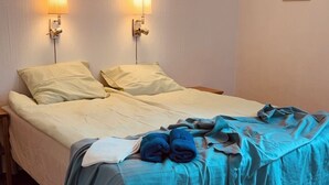 Una cama individual con edredón azul y dos lámparas fijadas a la pared.