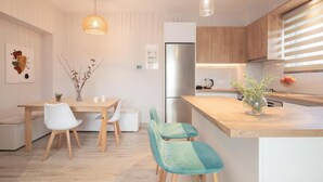 Eine moderne Küche mit Holzschränken, einem Edelstahlkühlschrank und einem Essbereich mit einem Holztisch und Stühlen.