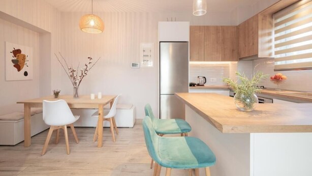 A modern kitchen with wooden cabinets, a stainless steel refrigerator, and a dining area with a wooden table and chairs. - !!New!! Andriana’s apartment
A fully equipped 2-BR apt in the countryside
 (Zakynthos)