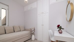 A minimalist room with a beige sofa, a white desk, and a white wardrobe. - !!New!! Andriana’s apartment
A fully equipped 2-BR apt in the countryside
 (Zakynthos)