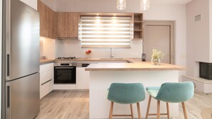 A modern kitchen with a central island, stainless steel appliances, wooden cabinets, and teal bar stools. - !!New!! Andriana’s apartment
A fully equipped 2-BR apt in the countryside
 (Zakynthos)