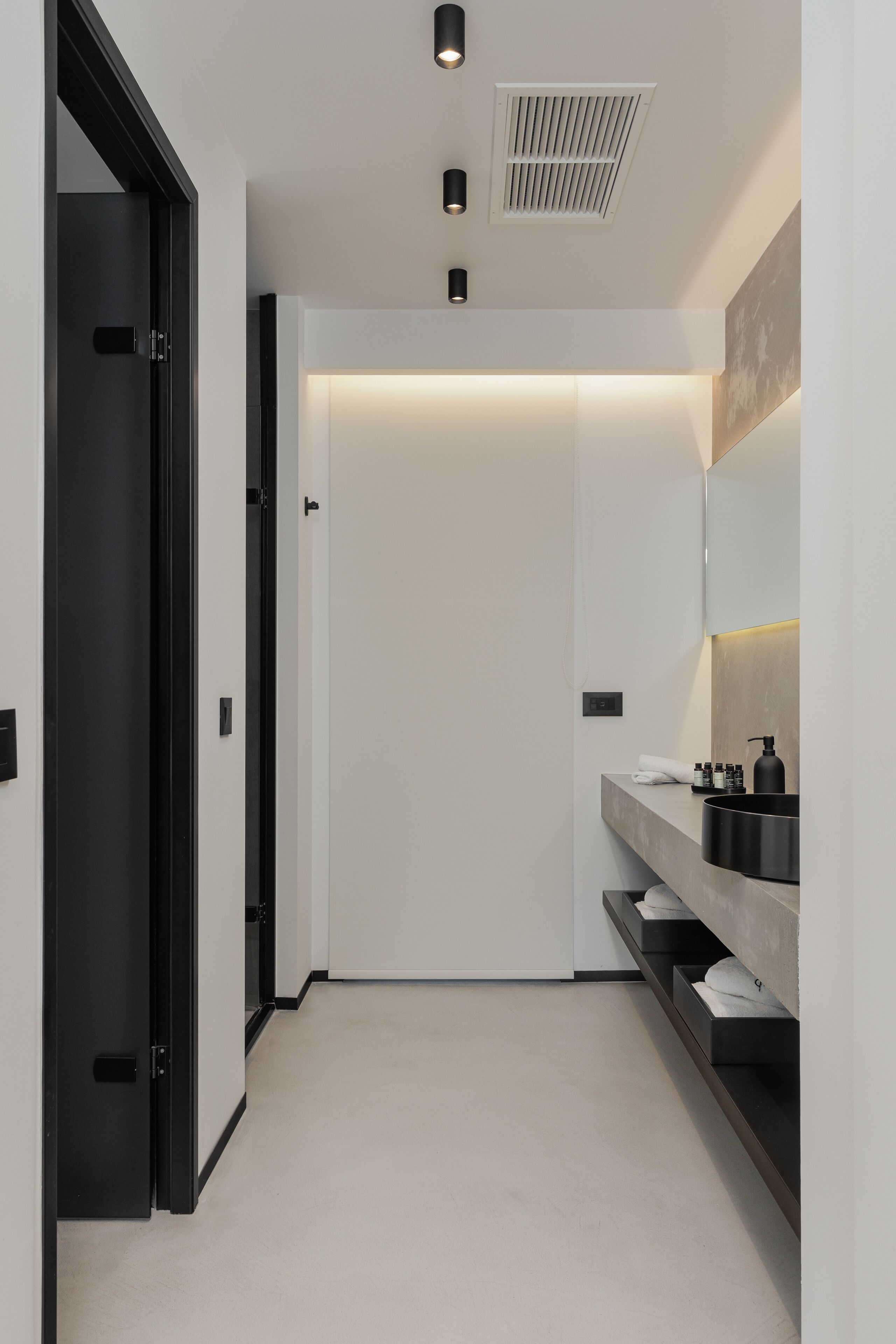 A modern bathroom with a minimalist design, featuring a large mirror, a built-in sink, and a towel rack.