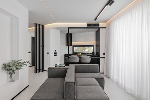 Una sala de estar moderna con un sofá seccional, un televisor de pantalla plana y un comedor con una mesa pequeña y sillas.