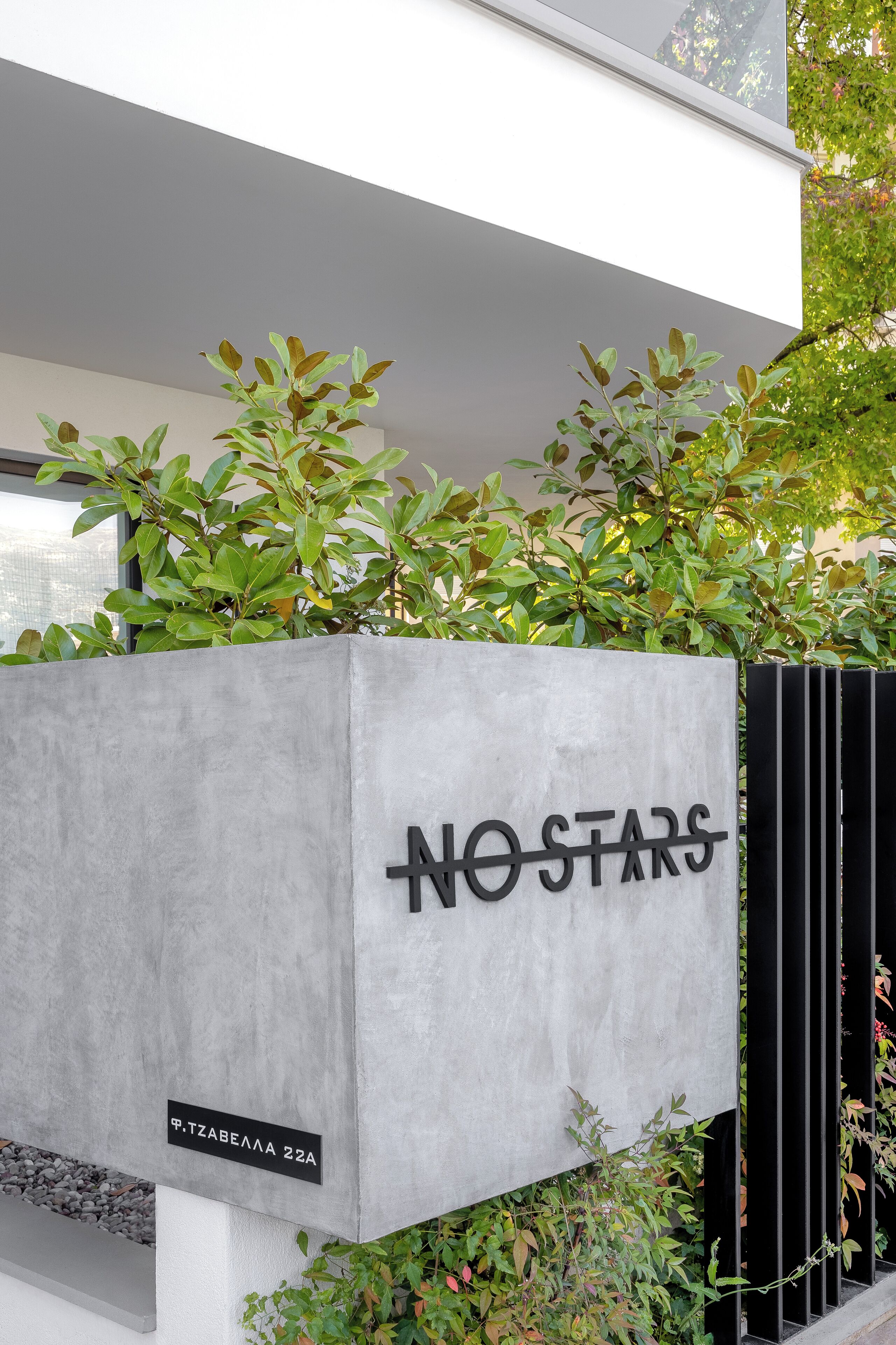Een modern gebouw met een betonnen gevel en een bord waarop staat 'NO STARS'.