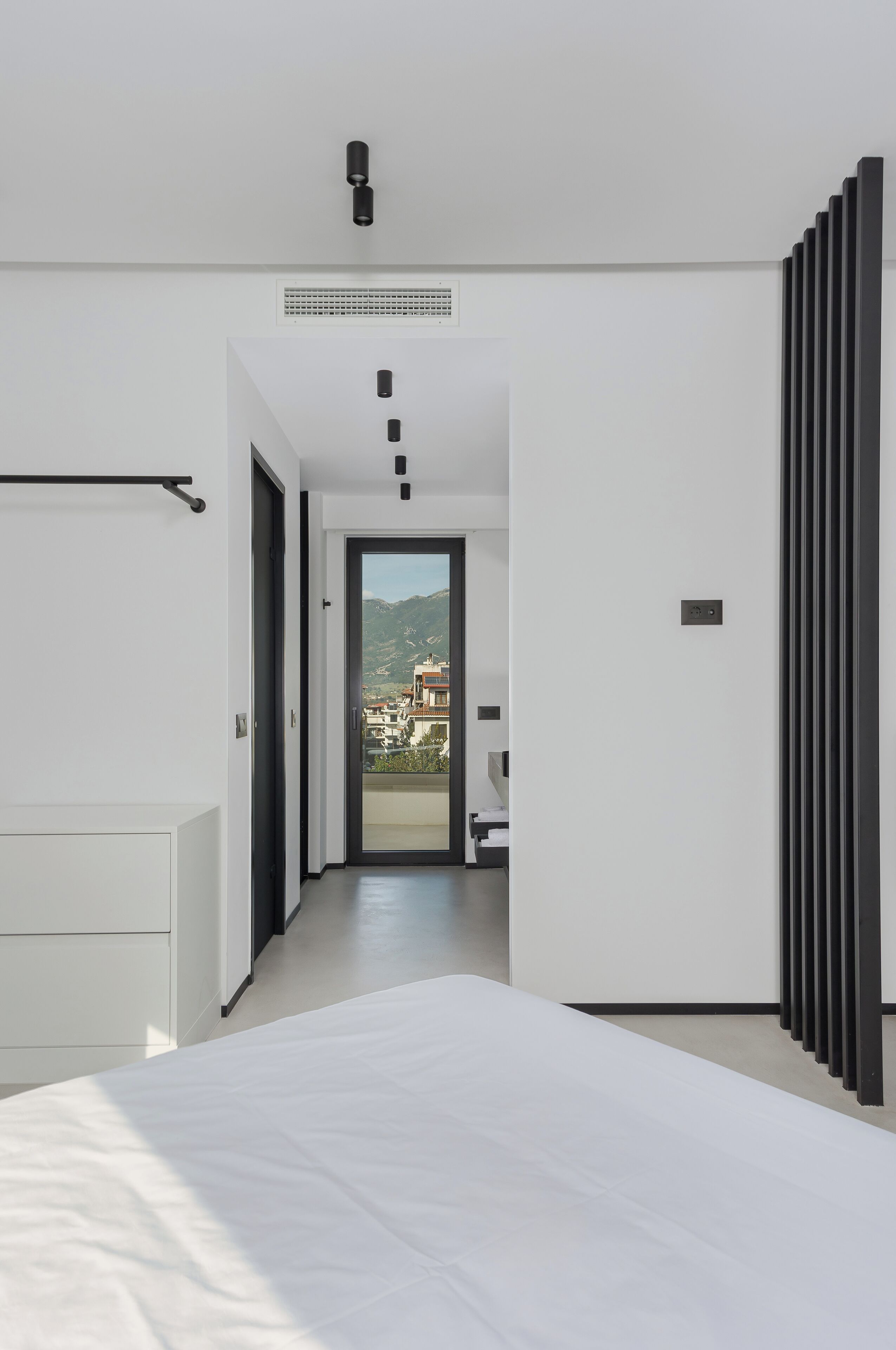 Habitación de hotel moderna con una cama grande, vistas a la ciudad y un balcón.
