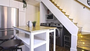 Una cocina compacta con refrigerador de acero inoxidable, lavadora y encimera de madera.