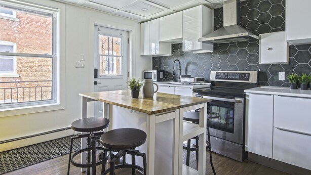 Una cocina moderna con armarios blancos, estufa de acero inoxidable y un salpicadero hexagonal.