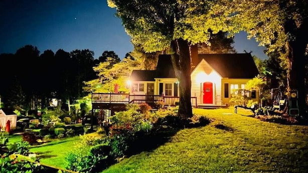 A house with a red door, surrounded by a well-maintained garden and trees. - Tiny House, Big Amenities – Home  (Asheville)
