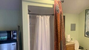 A bathroom with a shower curtain, a toilet, and a microwave. - Tiny House, Big Amenities – Home  (Asheville)