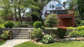 A house with a front porch, a stone staircase, and a well-maintained garden with various plants and a small tree. - Tiny House, Big Amenities – Home  (Asheville)