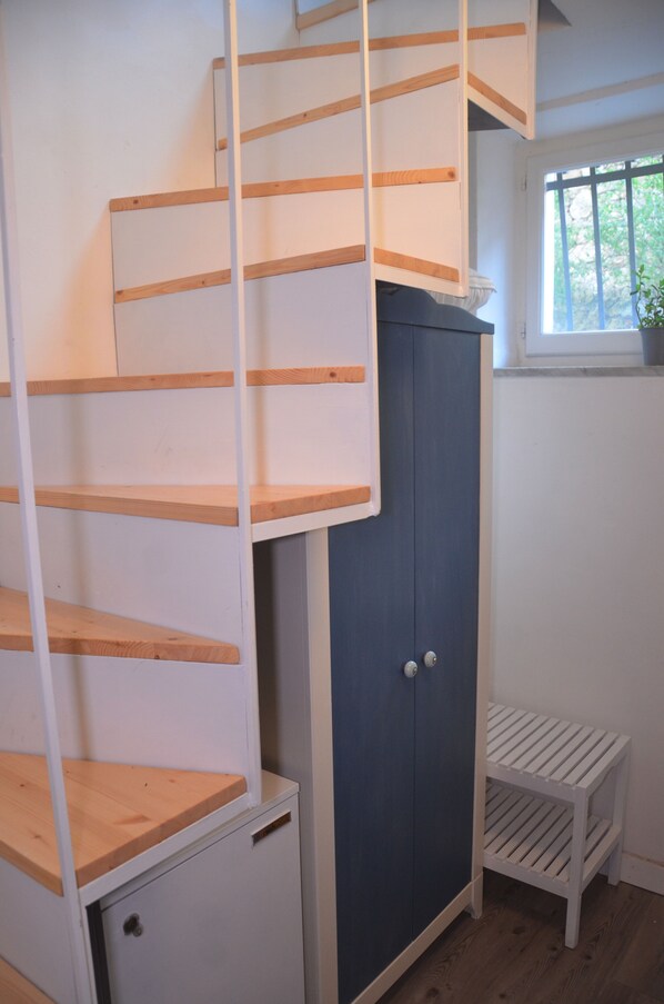 A staircase with wooden steps and white railings, a blue cabinet, and a small white bench.