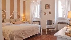 Une chambre à coucher avec un lit, une chaise, une table avec une lampe et une fenêtre avec des rideaux.
