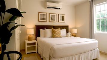 Habitación de hotel con una cama grande, dos mesitas de noche con lámparas, un aire acondicionado de pared y cuadros enmarcados sobre la cama.