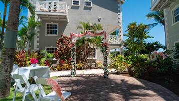 Un cortile con un gazebo bianco, posti a sedere all'aperto e piante tropicali rigogliose.