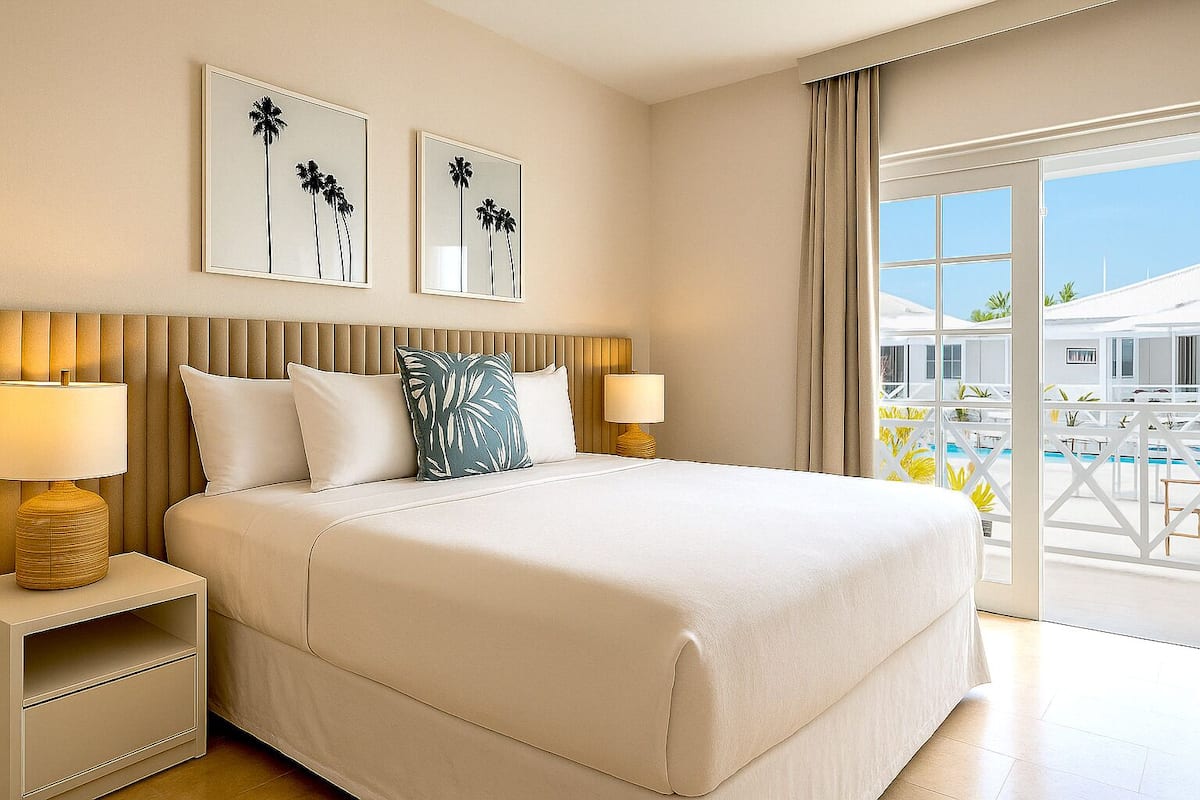 A hotel room with a large bed, two bedside tables with lamps, a headboard, and two framed pictures on the wall.