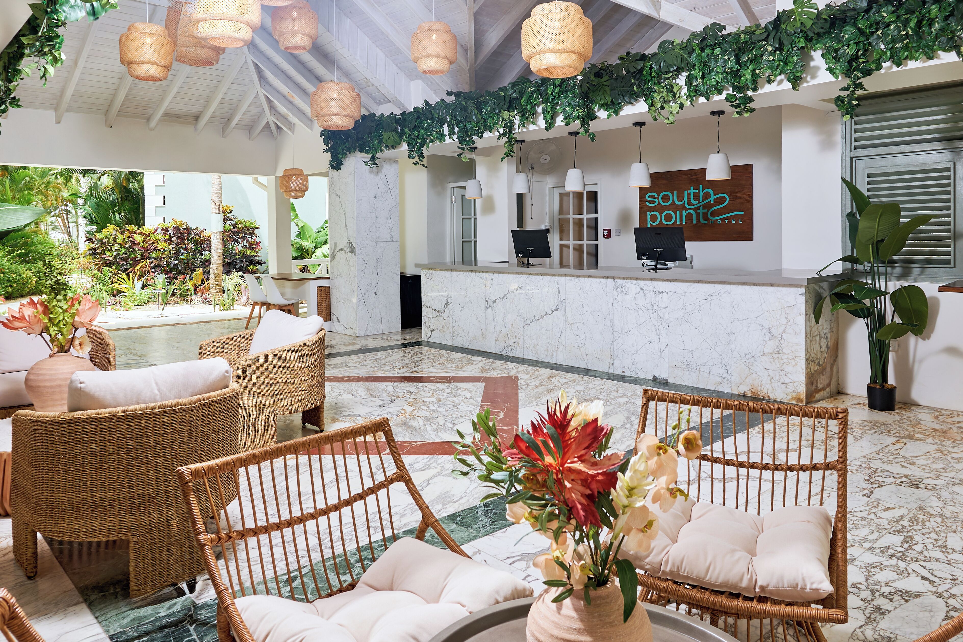 A hotel lobby with wicker furniture, a reception desk, and a sign that reads "south point hotel".