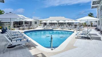 Una piscina al aire libre, sombrillas, sillones reclinables de piscina