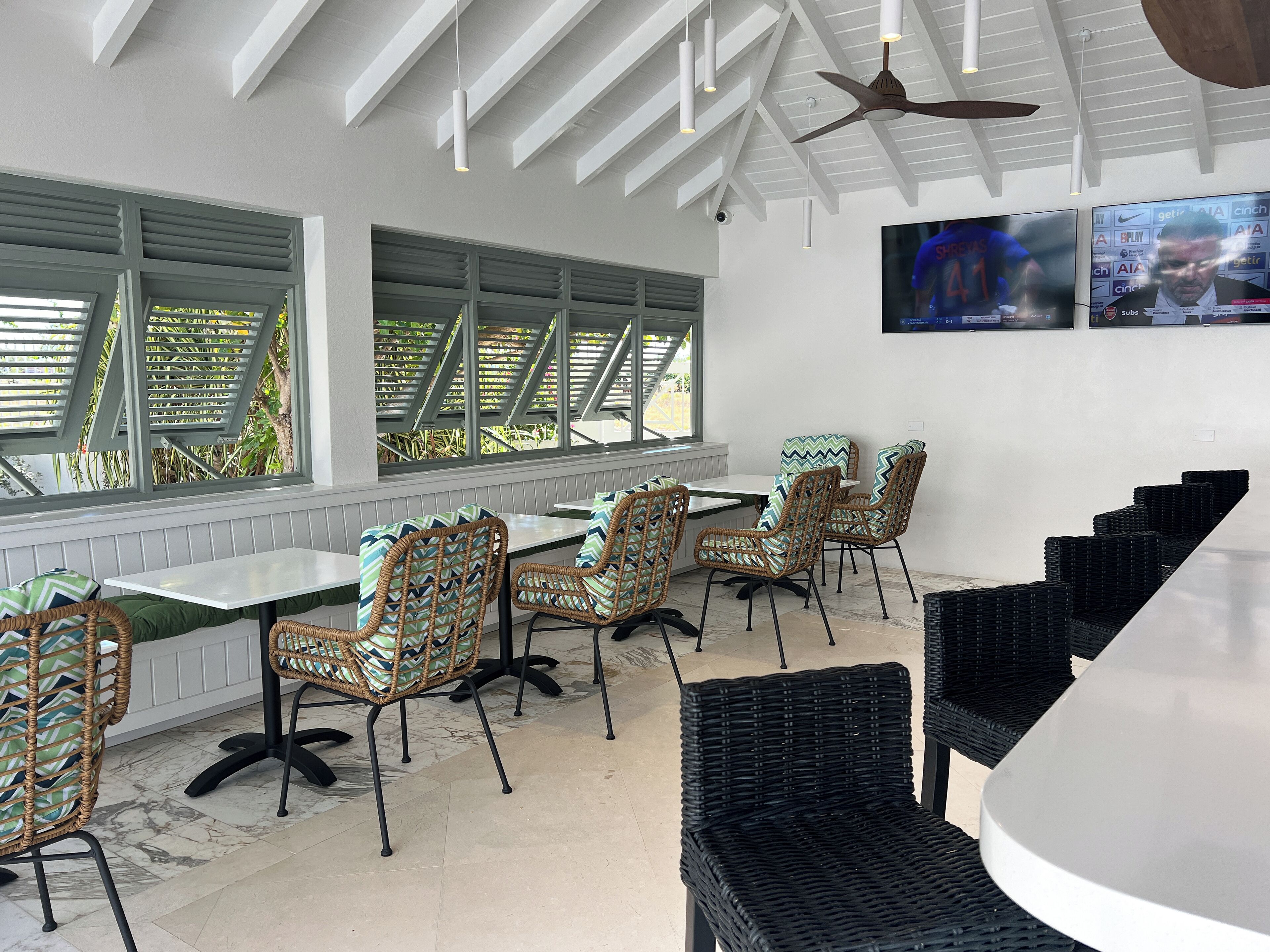 A modern dining area with wicker chairs, a white table, and a ceiling fan.
