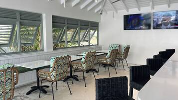 A modern dining area with wicker chairs, a white table, and a ceiling fan.