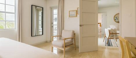 Une chambre d’hôtel comprenant un lit, une chaise, un bureau et une porte donnant sur une autre pièce.