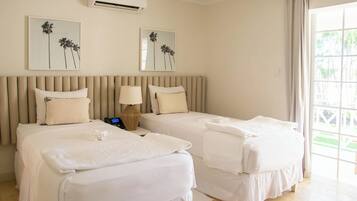 A hotel room with two beds, a bedside table with a lamp, and two wall-mounted air conditioning units.