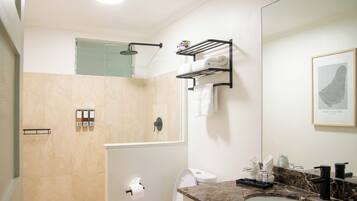 Een moderne badkamer met douche, toilet en wastafel.