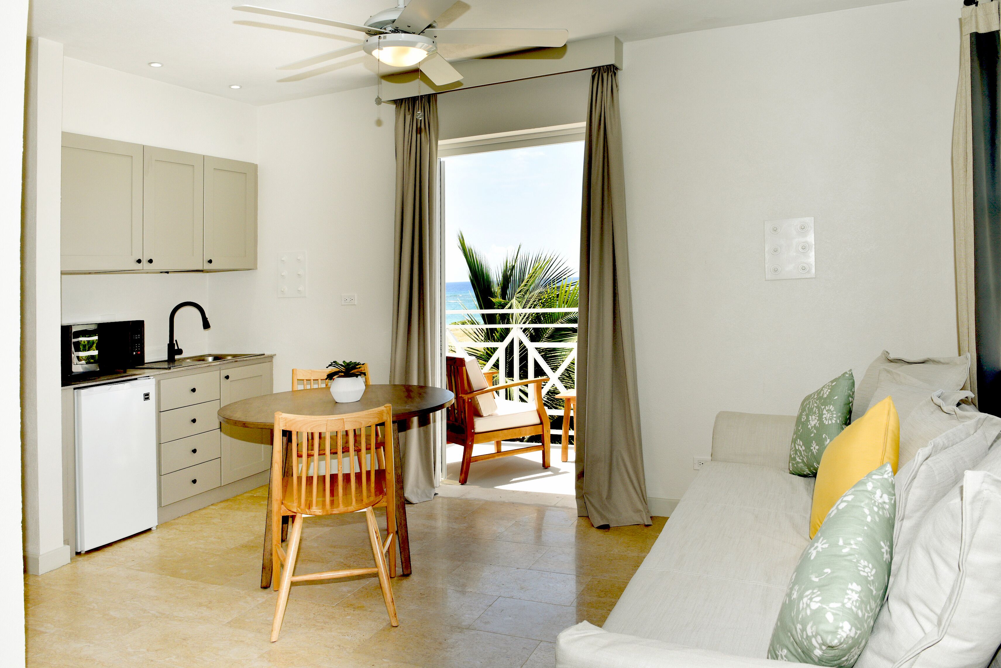 A compact living space with a kitchenette, dining area, and a balcony with a view.