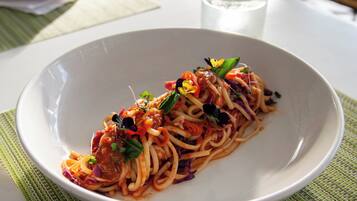 A plate of spaghetti with vegetables and herbs.