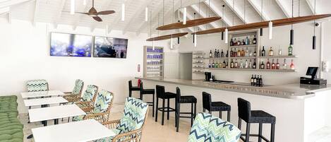 A bar area with wicker chairs, a bar counter, and ceiling fans.