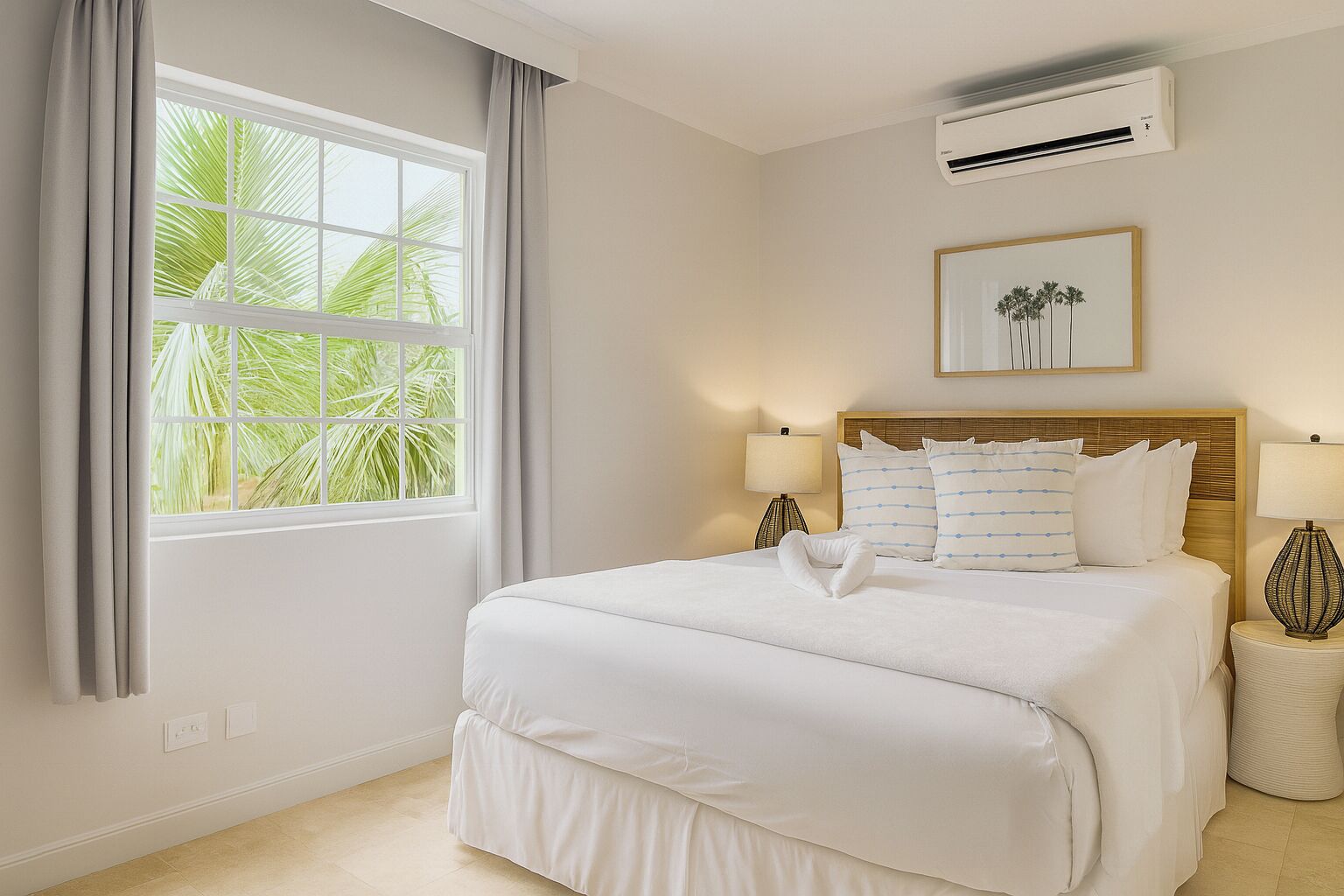 Een hotelkamer met een groot bed, twee nachtkastjes, een raam met gordijnen, een airconditioner en een ingelijste foto aan de muur.
