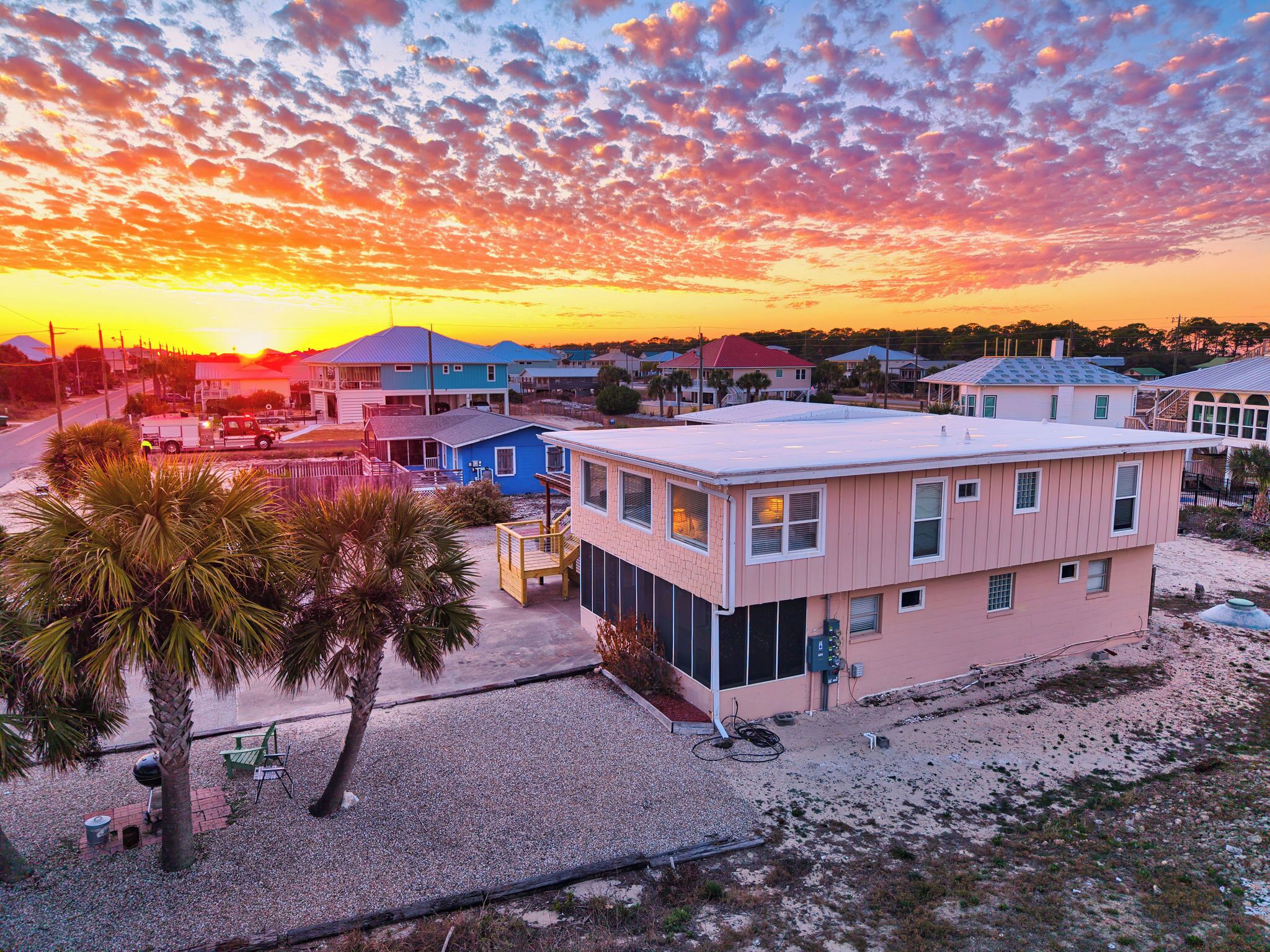 Zona residencial costeira com casas, céu claro e um pôr do sol.