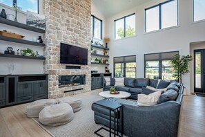 Una sala moderna con chimenea de piedra, sofás grises y televisor de pantalla plana.