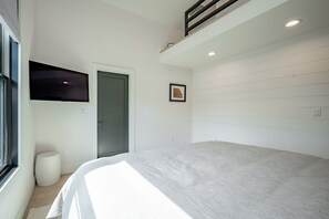 Una camera da letto con un letto, una porta, una finestra e una televisione a muro.