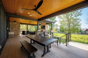 Un patio al aire libre con chimenea de piedra, terraza de madera y vistas del paisaje circundante.