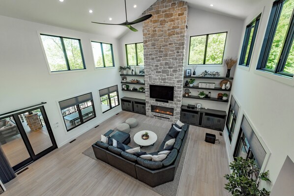 A spacious living area with a stone fireplace, large windows, and a modern sofa.