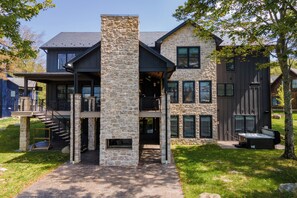 Ein modernes, zweistöckiges Haus mit Naturstein-Fassade, zahlreichen Fenstern und einer überdachten Außenfläche.