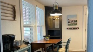 A dining area with a wooden table and chairs, a coffee machine, and a blue cart with shelves. - BEAUTIFUL LAKE HAMILTON COTTAGE - GREAT LOCATION, GREAT VIEWS - ADORABLE  3BD/3B (Hot Springs)