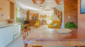 A modern kitchen with a dining area, wooden accents, and a staircase. - IM05 Apto 3 Quartos - Riverside Imbassaí (Mata de São João)