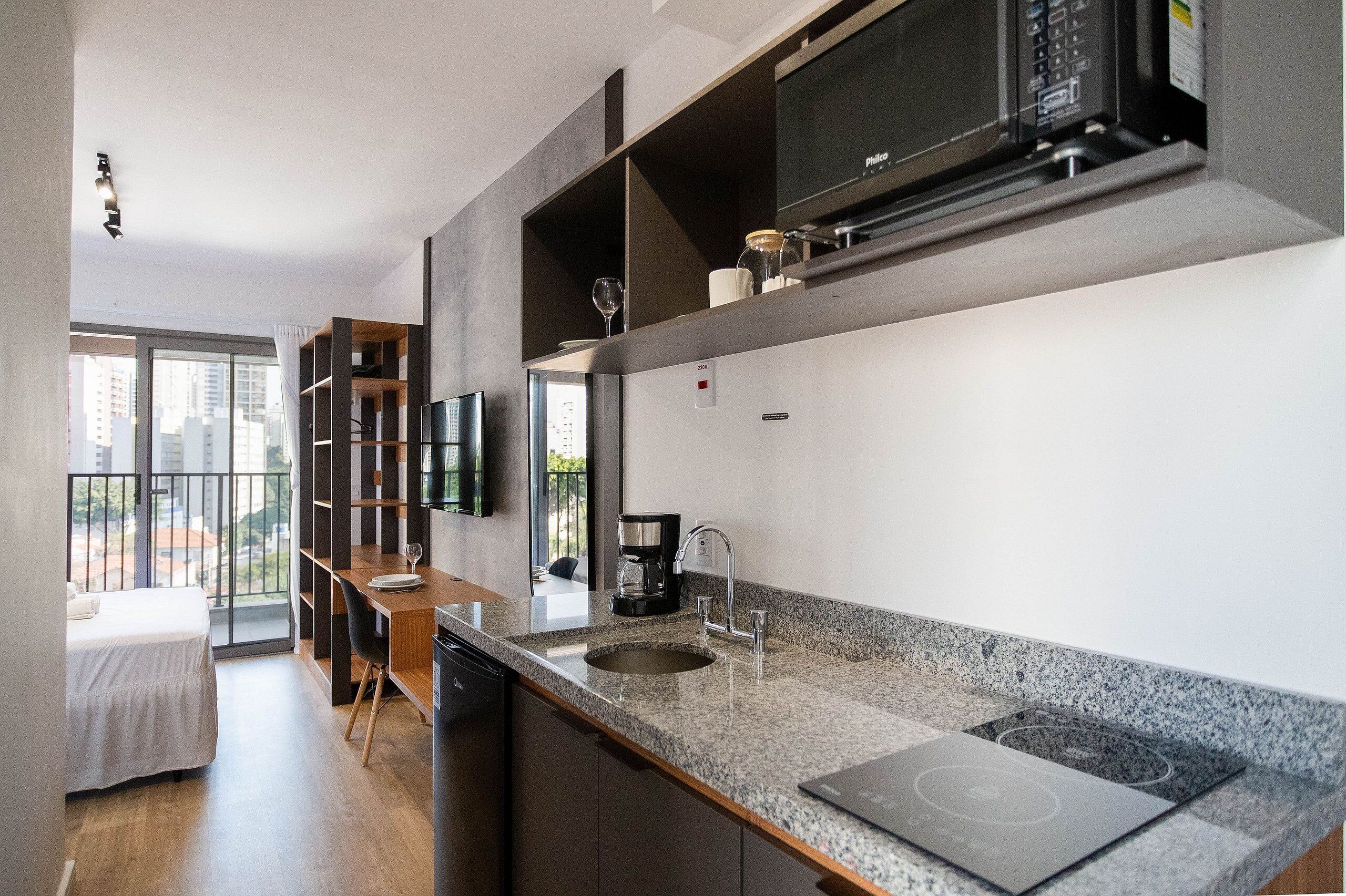 A modern kitchen with a granite countertop, built-in microwave, and a coffee maker.